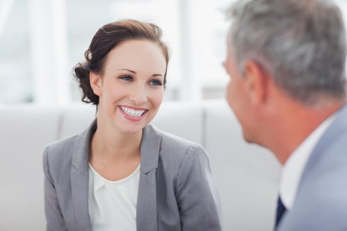 Cheerful businesswoman listening to her workmate talking in bright office