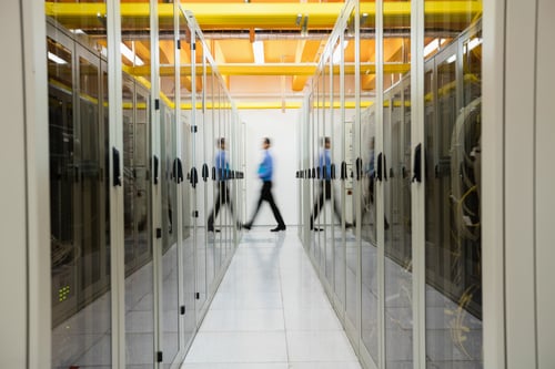 Data Center Systems Data Center Design Technician Walking Through Hallway of Servers