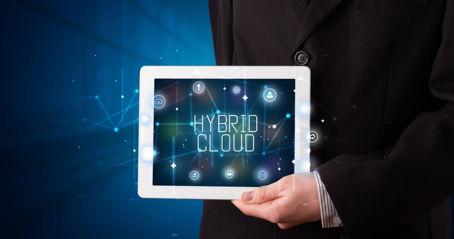 Young business person working on tablet and shows the digital sign: HYBRID CLOUD